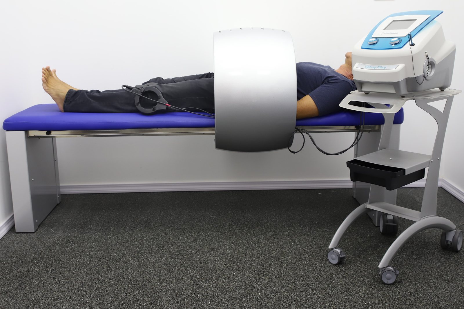 Patient lying on the PainFree treatment bed with the ring applicator over the lower body